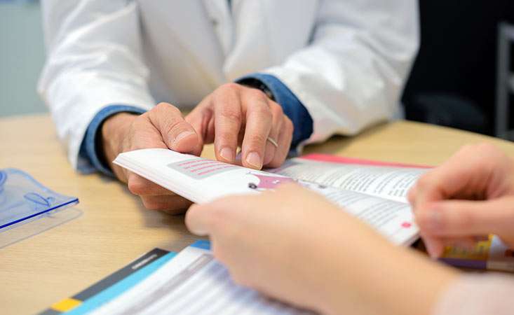 Doctor showing booklet to patient 733x450 1